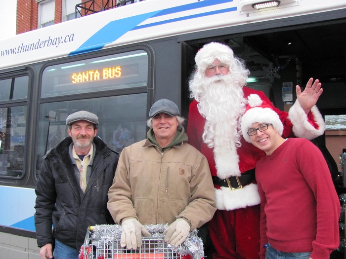 Santa, his helper and two others in the doorway of the Santa Bus