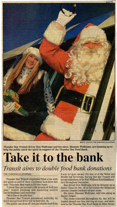 Santa standing in the doorway of a bus with a young elf beside him