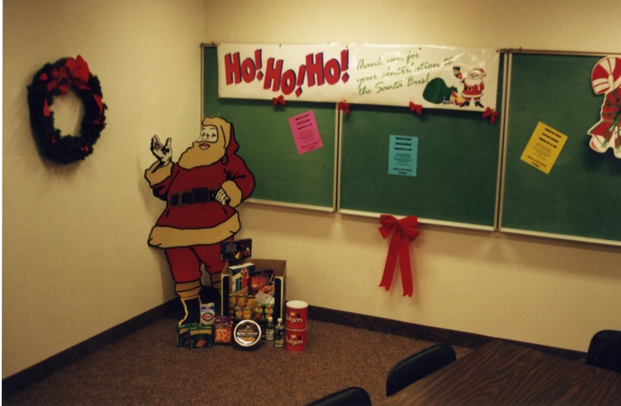 a cut out of Santa in a corner in front of a chalkboard.