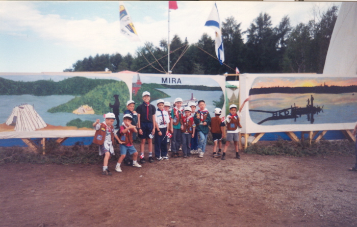 A group of young boys standing in front of an airplane with flags 