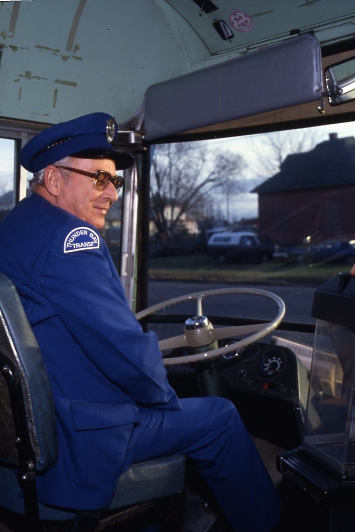 a bus driver sitting in the driver's seat of a bus