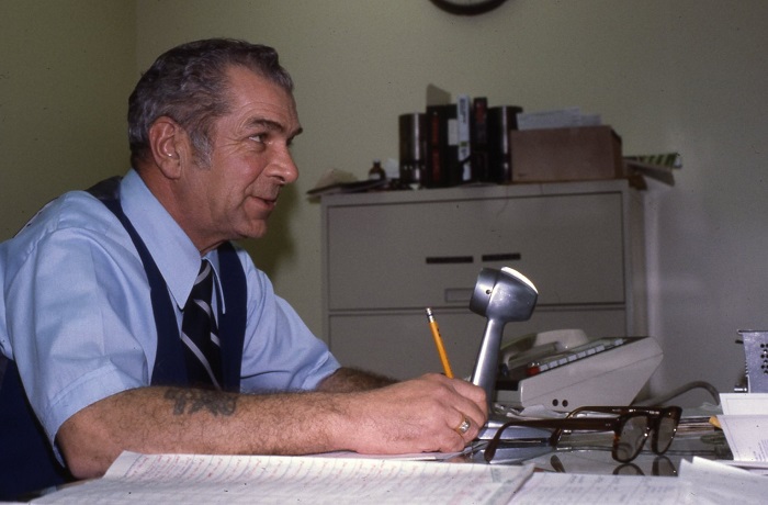 A man sitting in front of a microphone holding a pen 