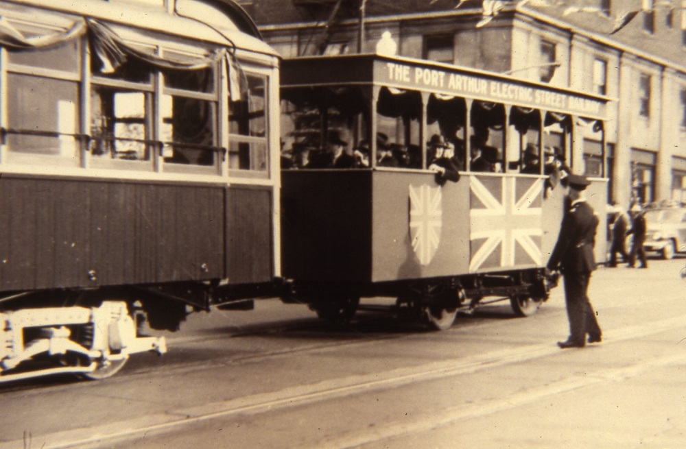 a streetcar going down a street with its back car full of passengers
