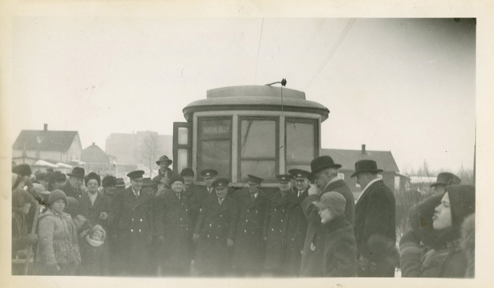a crowd of people gathering in front of a streetcar