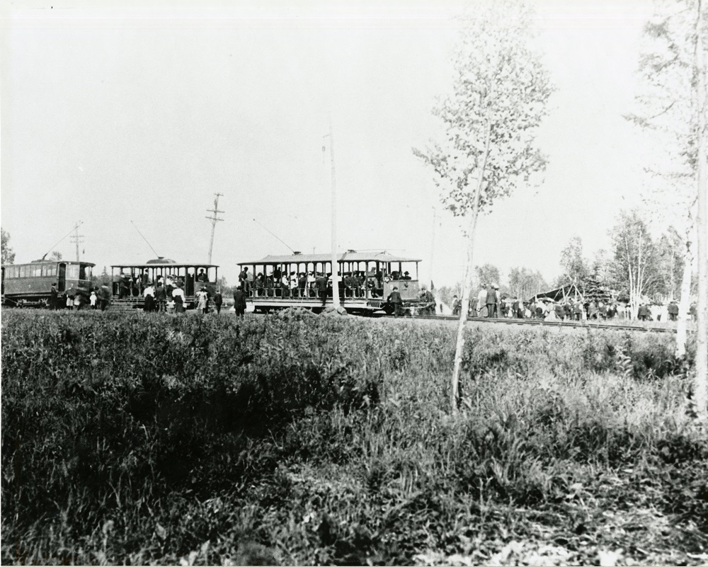 passenger cars full of people proceeding down a track