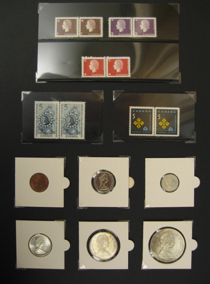 Various small coins and stamps are taped to a black sheet 