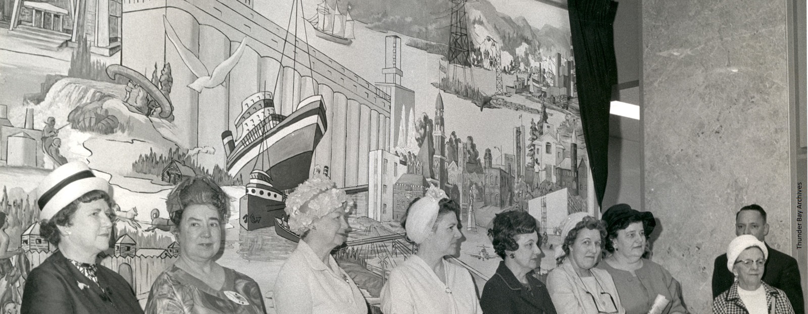 A group of women standing in front of a mural in city hall 