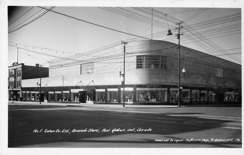 A round edged store front sitting on the corner of two streets with electric lines in front