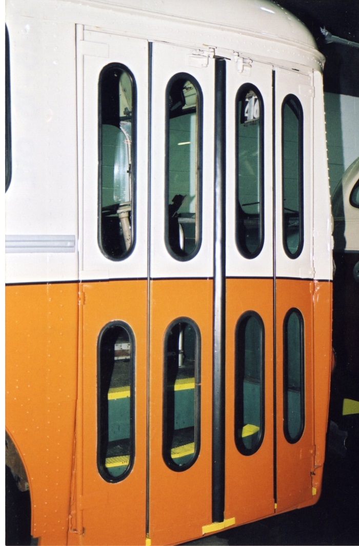 A restored orange and white trolley bus doorway is shown closed