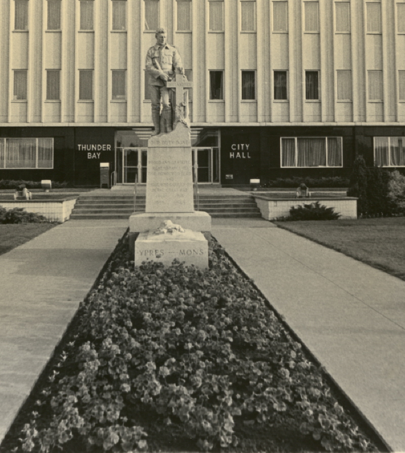 A statue of a soldier in the middle of a path to the entrance of City Hall