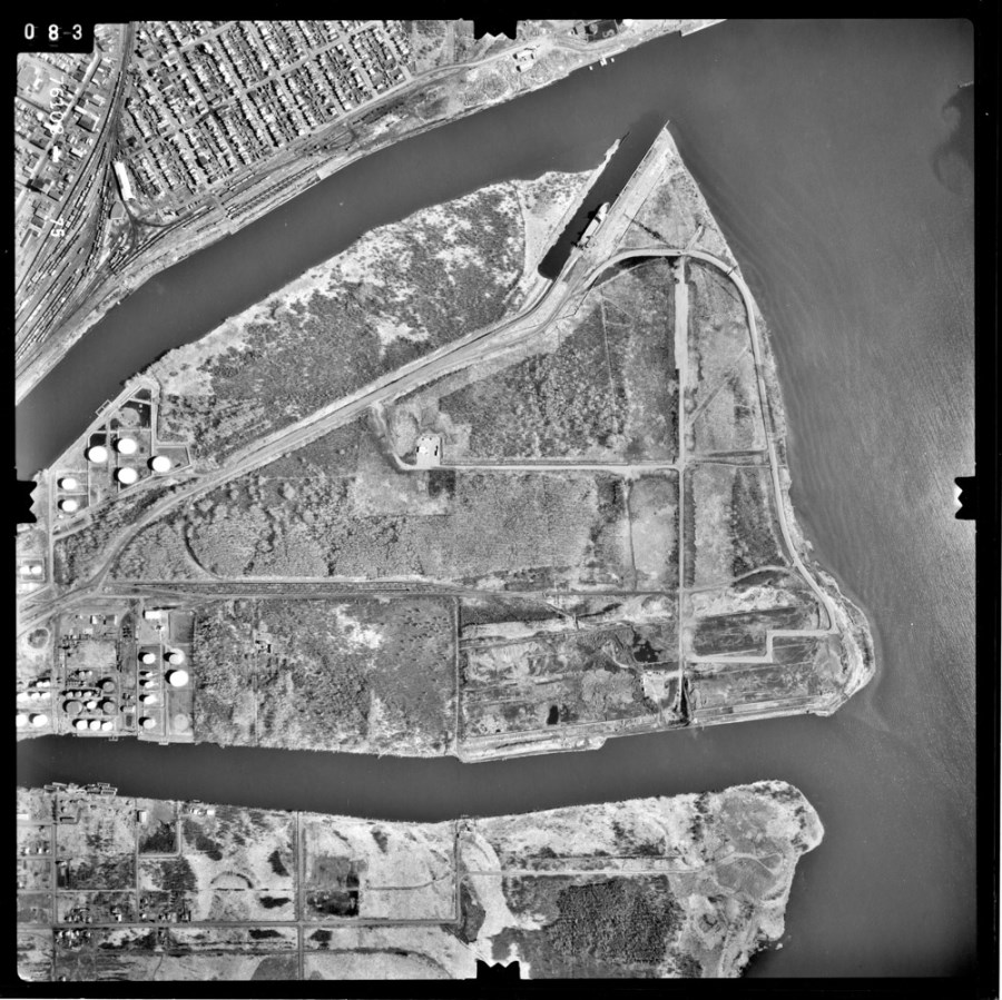A black and white aerial photo showing the waterfront and surrounding area  