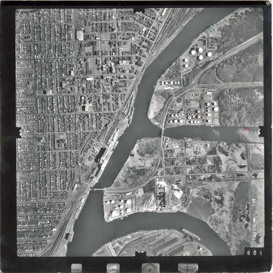 A black and white aerial photo showing the waterfront and surrounding area  