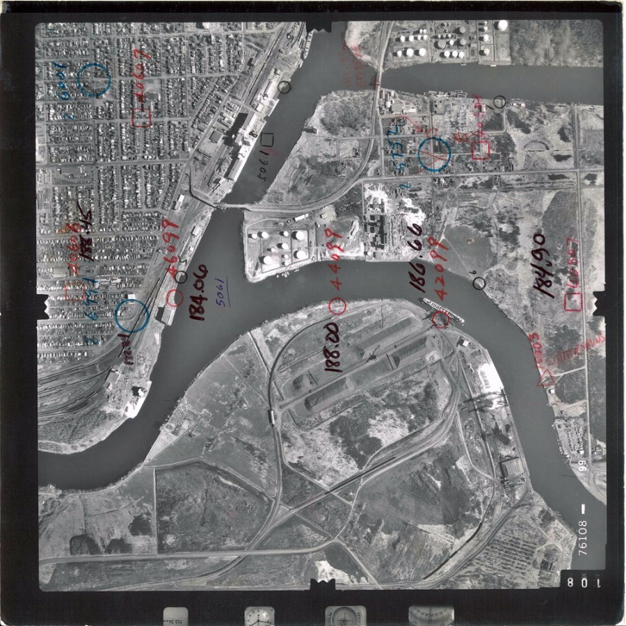 A black and white aerial photo showing the waterfront and surrounding area  