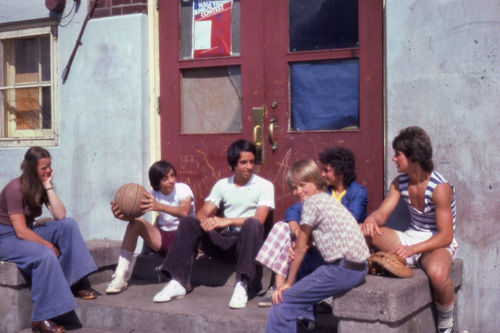 A group of people sitting on the steps in front of a building