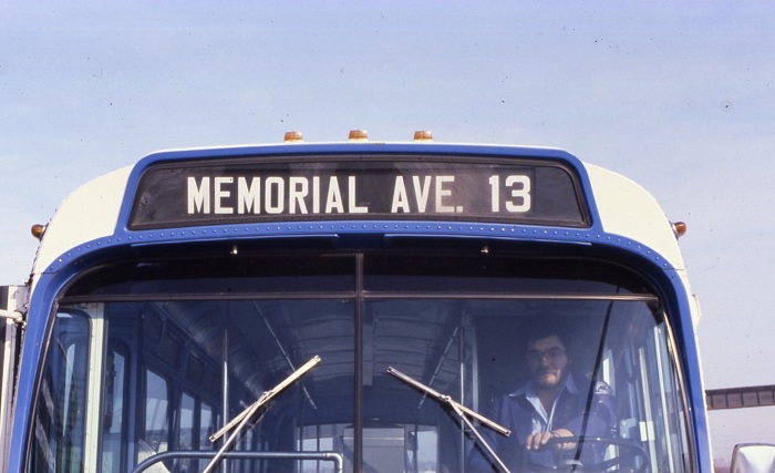 top front of a bus. The driver is visible through the windshield. 