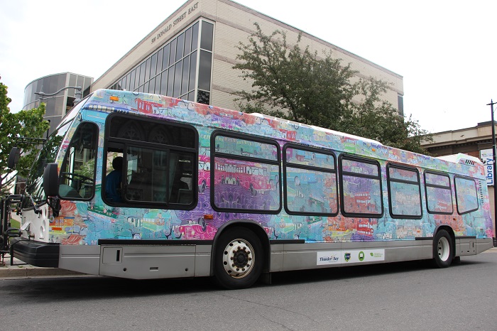 A bus decorated with blue, pink, purple and green paint 