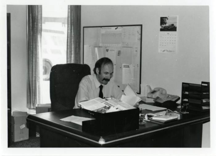 A man sitting reading a document at his desk in an office