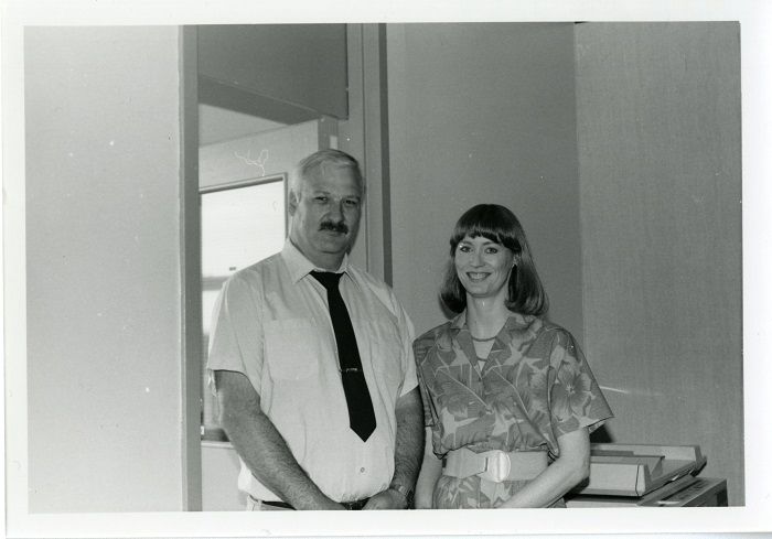 Two people standing side by side and smiling at the camera