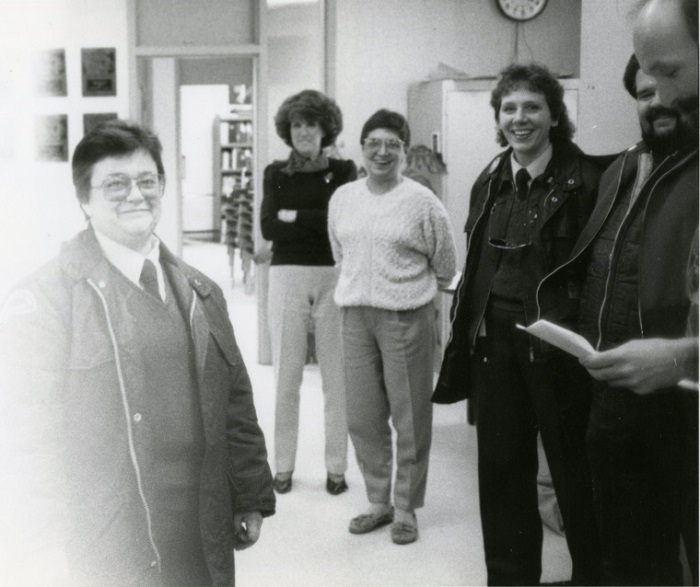 A group of people standing facing the camera and smiling in an open room