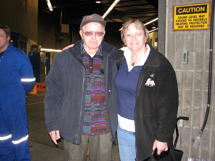 Two people standing and smiling at the camera in a garage 