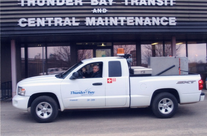 A person sitting in a white City of Thunder Bay pickup truck in front of the transit building