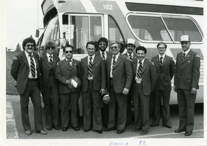 A group of transit drivers standing in front of a bus - black and white