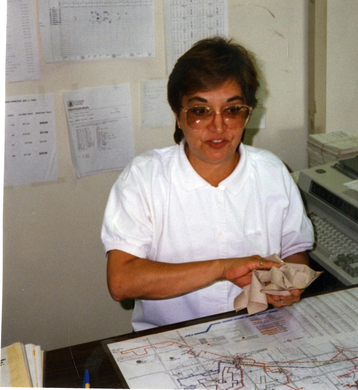 A woman sitting at a desk wiping her hands with a towel and wearing large glasses