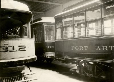two Port Arthur trolley cars sitting side by side in a warehouse
