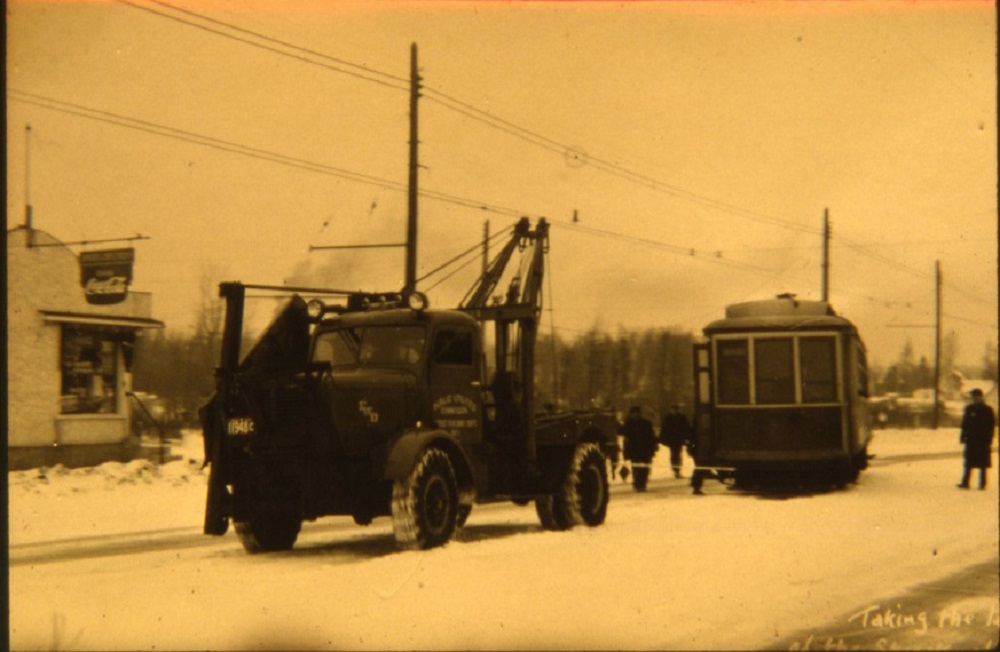 tow truck pulling a streetcar on a snow covered road