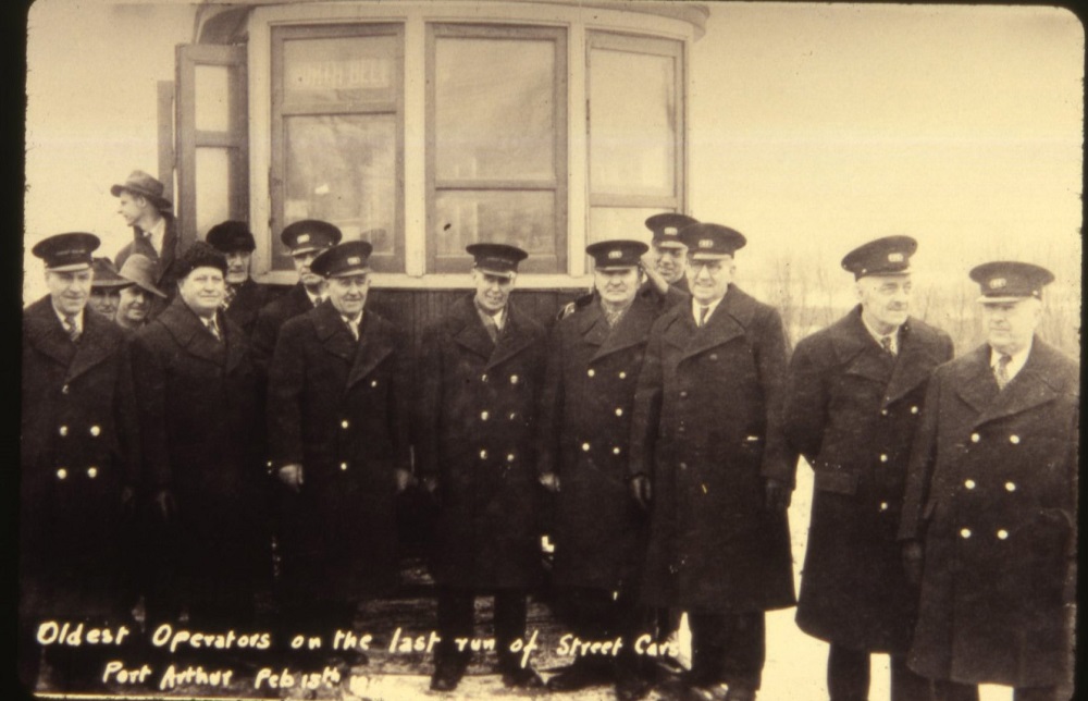 15 operators in uniforms standing in front of a streetcar