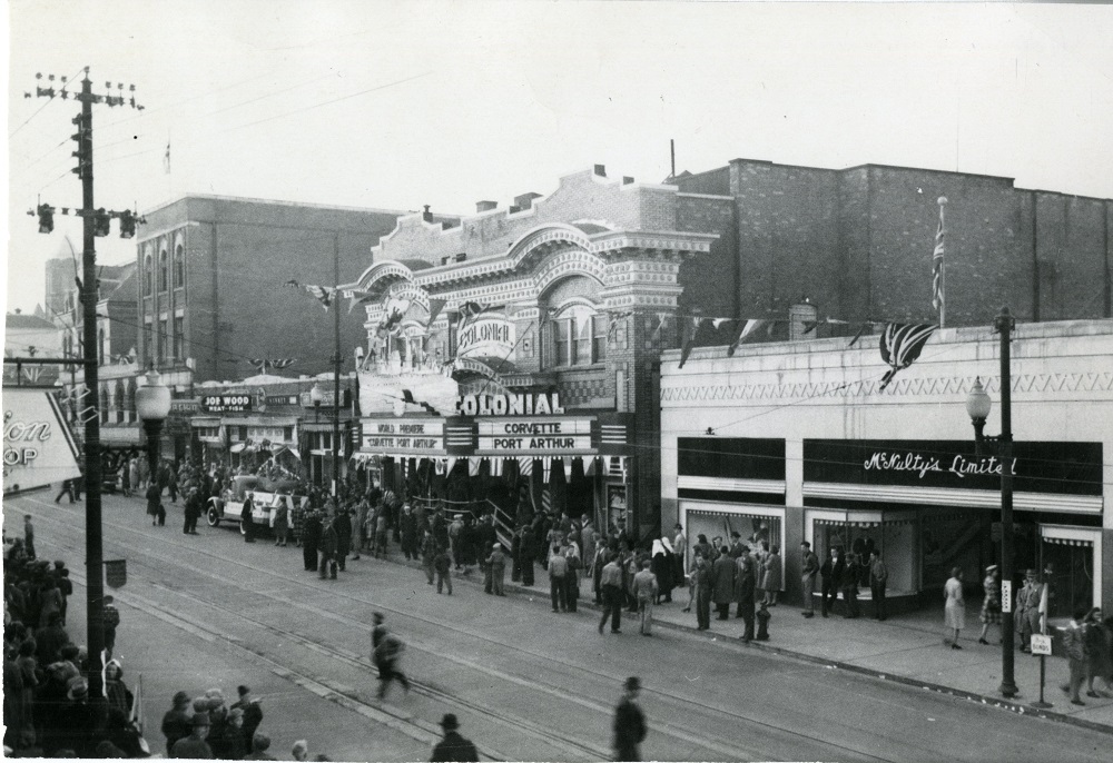 a busy street scene with people gathered around the Colonial Theatre.