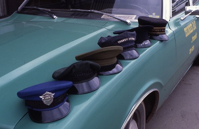 Various conductors hats sitting on the hood of a car showing change in uniform through the years