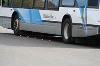 the bottom half of a blue and gray bus is pictured driving on the road