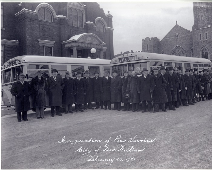A group of men standing in front of two buses