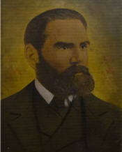 Mayor Squier sits wearing a black suit, and has a large beard 