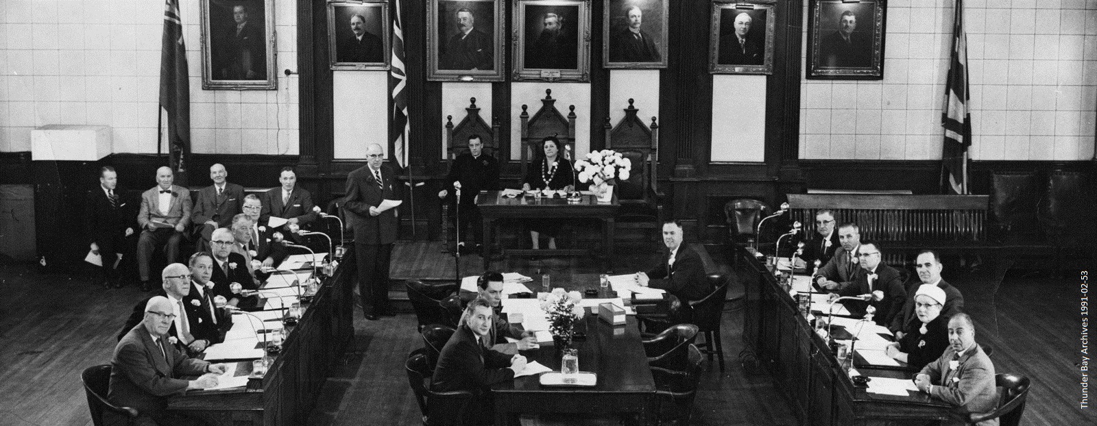 Council members seated at a square table with an open end towards the camera