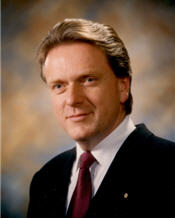 Mayor David Hamilton in front of a brown background wearing a suit