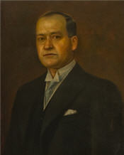 Mayor Murphy wearing a black suit, blue tie and stands for his mayoral painting 