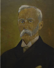 Mayor Clavet sits wearing a suit, with a large white moustache