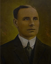 Mayor George Gibbon sits wearing a black suit and red tie 