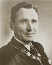 Mayor Badanai sitting for his black and white photogrpah wearing a suit and official necklace