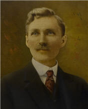 Mayor Issac Matthews sits wearing a suit with a red tie, and large moustache