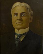 Mayor Hourigan sits wearing a black suit and blue tie 