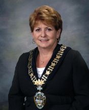 Mayor Lynn Peterson in front of a grey background wearing a suit and large necklace