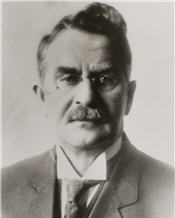 Mayor Vigars sits wearing a suit and small glasses