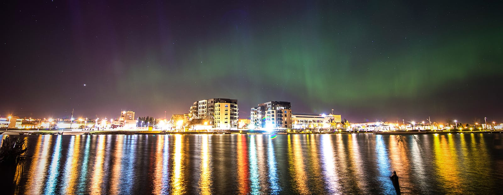 northern lights over city on waterfront