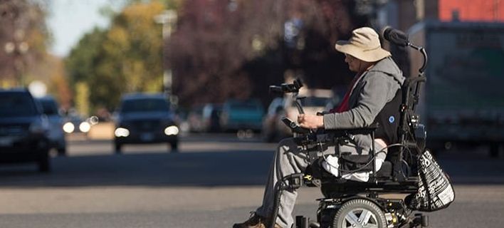 A person crossing a street in a wheelchair