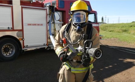 firefighter holding hose in front of fire truck