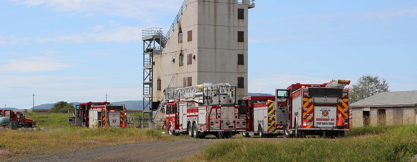 several fire trucks in field in front of a structure