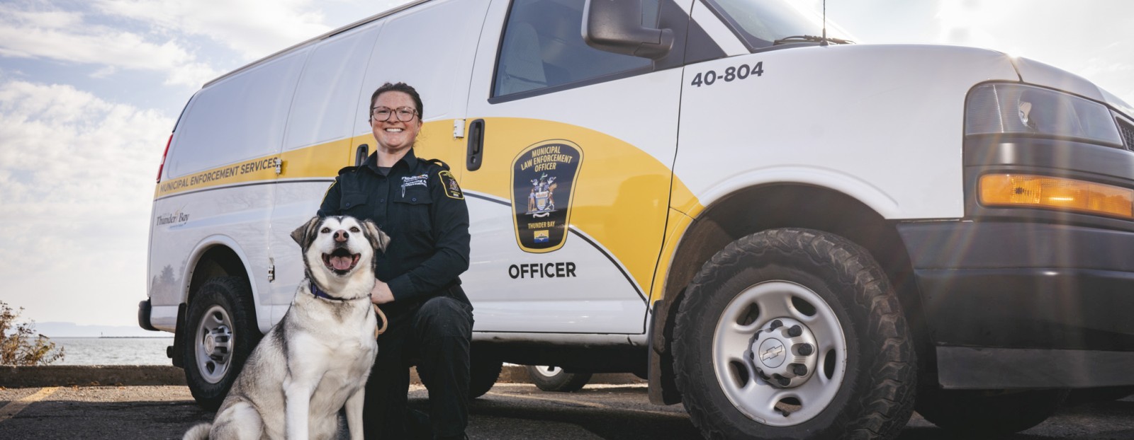 Municipal Enforcement Officer with a dog in front of a vehicle
